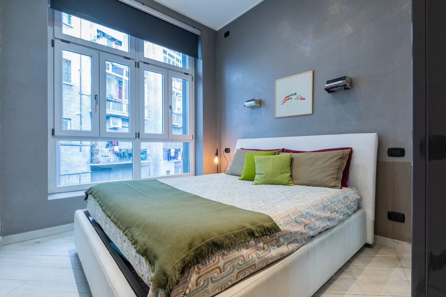 A bedroom with a bed beside a large multi-pane window.