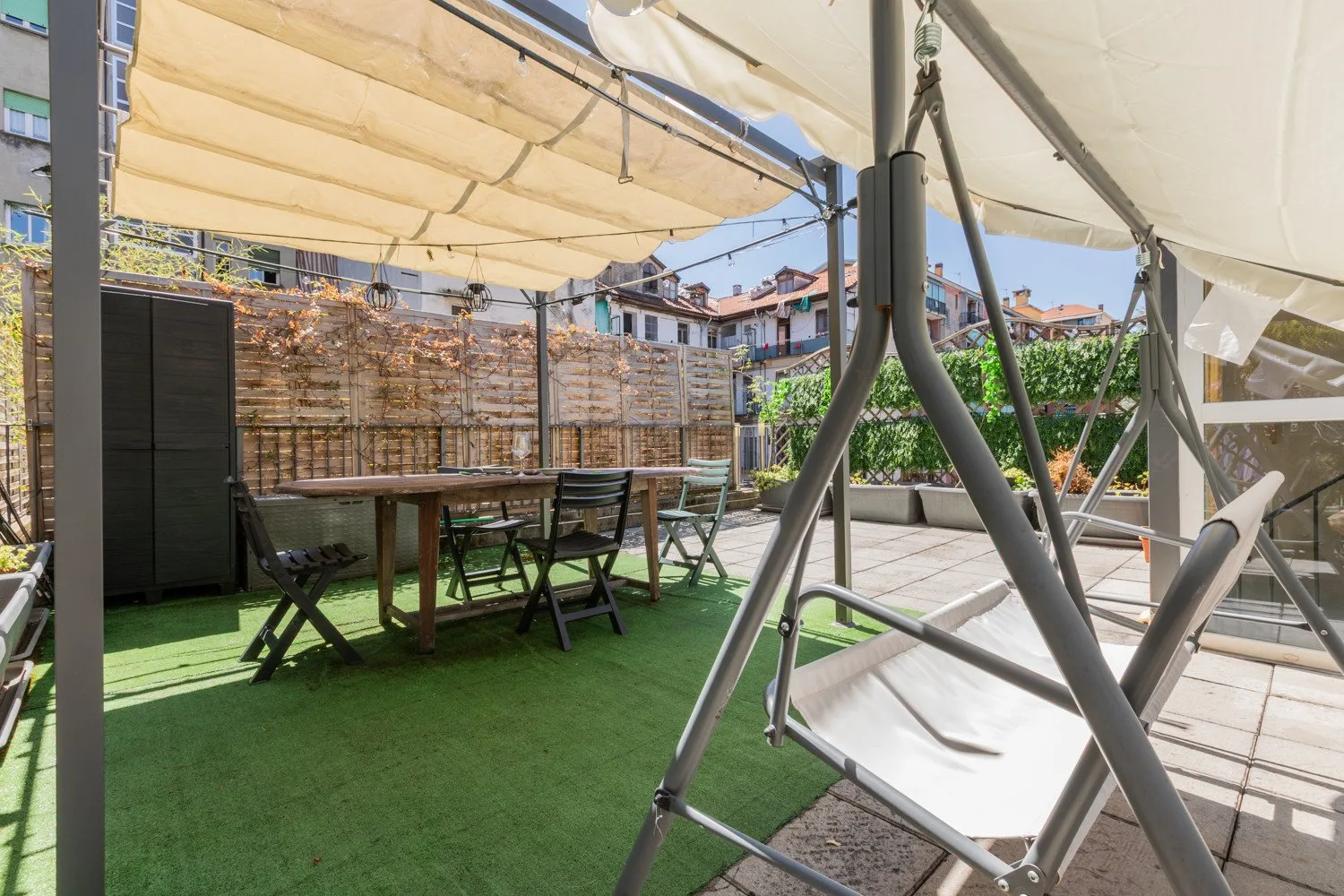 An outdoor patio with a dining table, seating, and a covered swing.