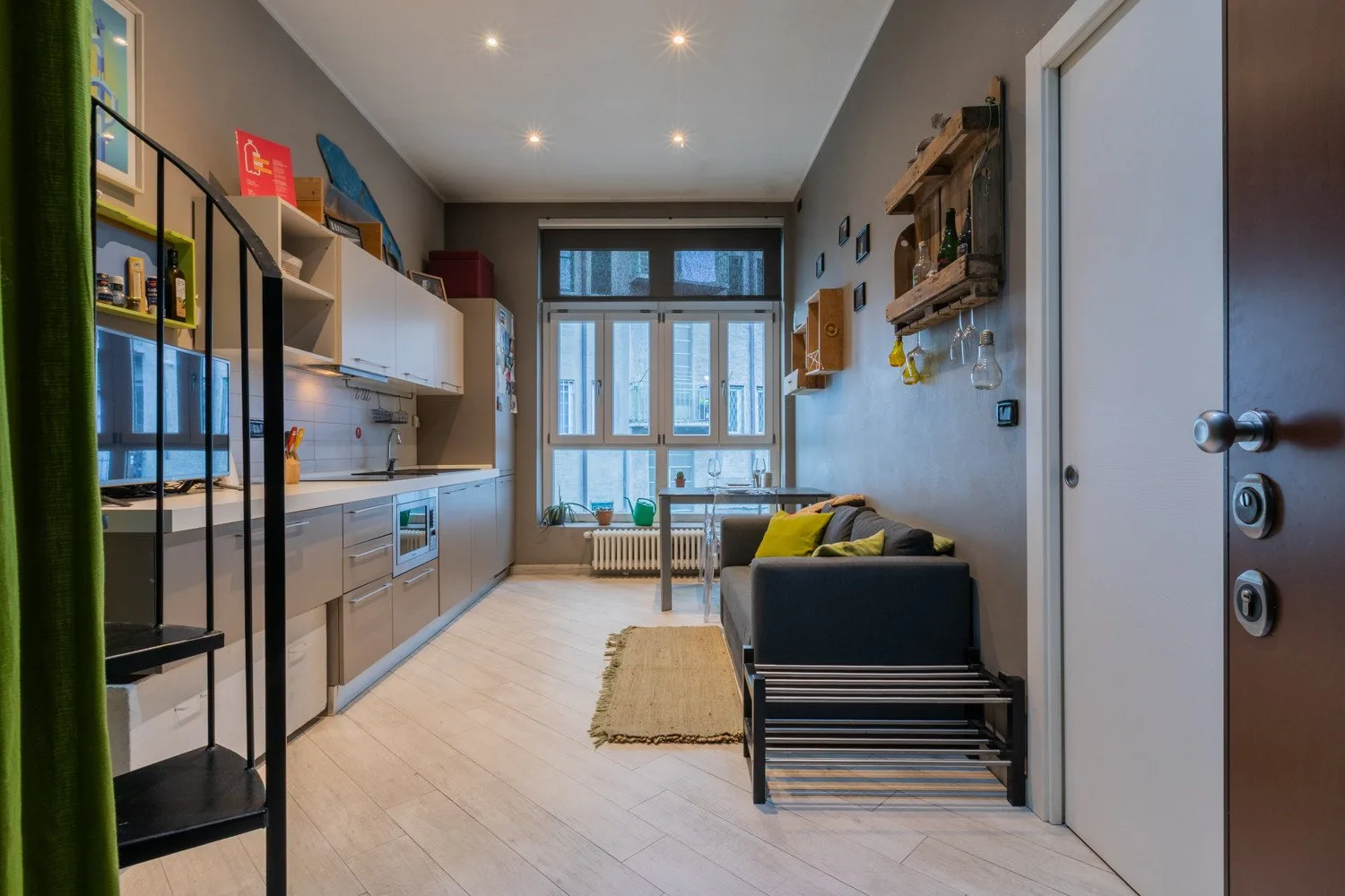 A compact kitchen and living area with a sofa beside the window.