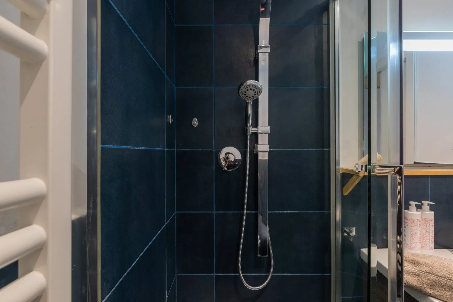 A tiled shower with a handheld showerhead and glass enclosure.