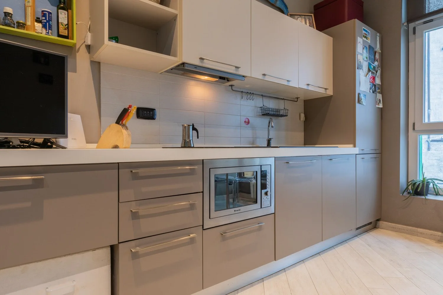 A modern kitchen with white cabinets, a countertop, and built-in appliances.