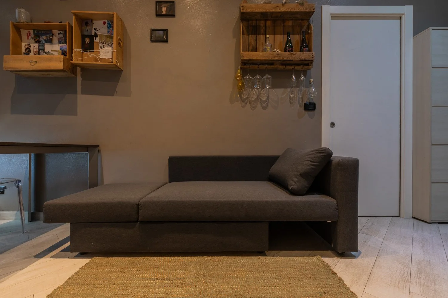 A living room with a dark sectional sofa and wall-mounted wooden shelves.