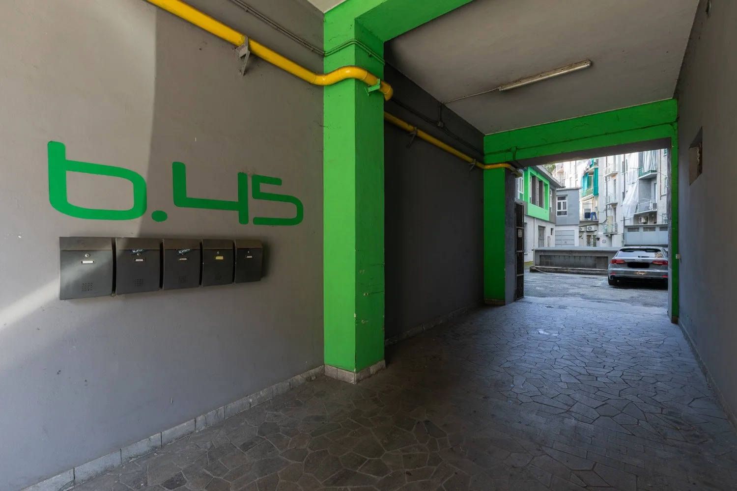 A covered passageway with green beams opens onto a courtyard.