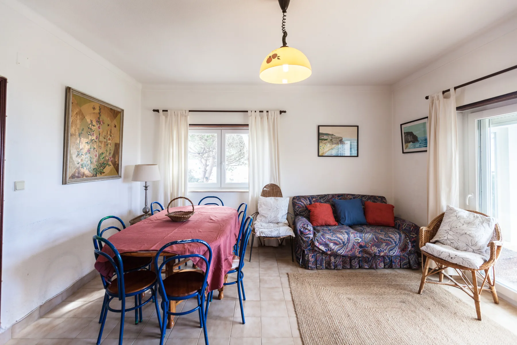 A living and dining area with a table, seating, and large windows.