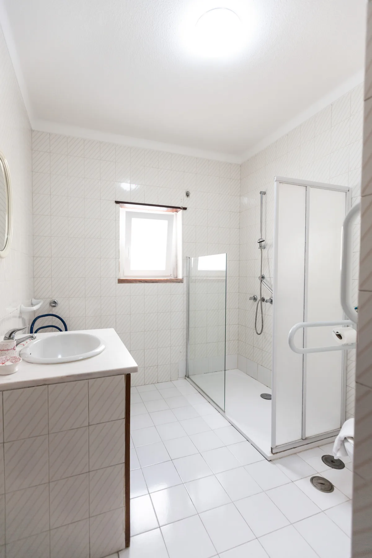 A tiled bathroom with a sink, mirror, and glass shower.