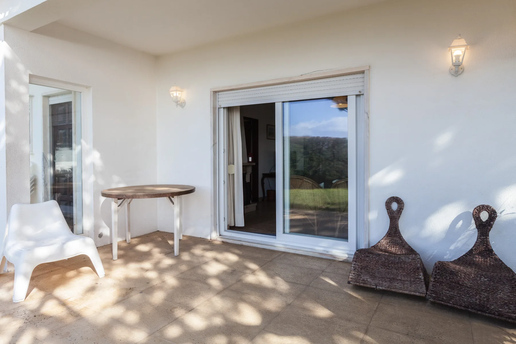 A sunlit patio with sliding glass doors and outdoor seating.