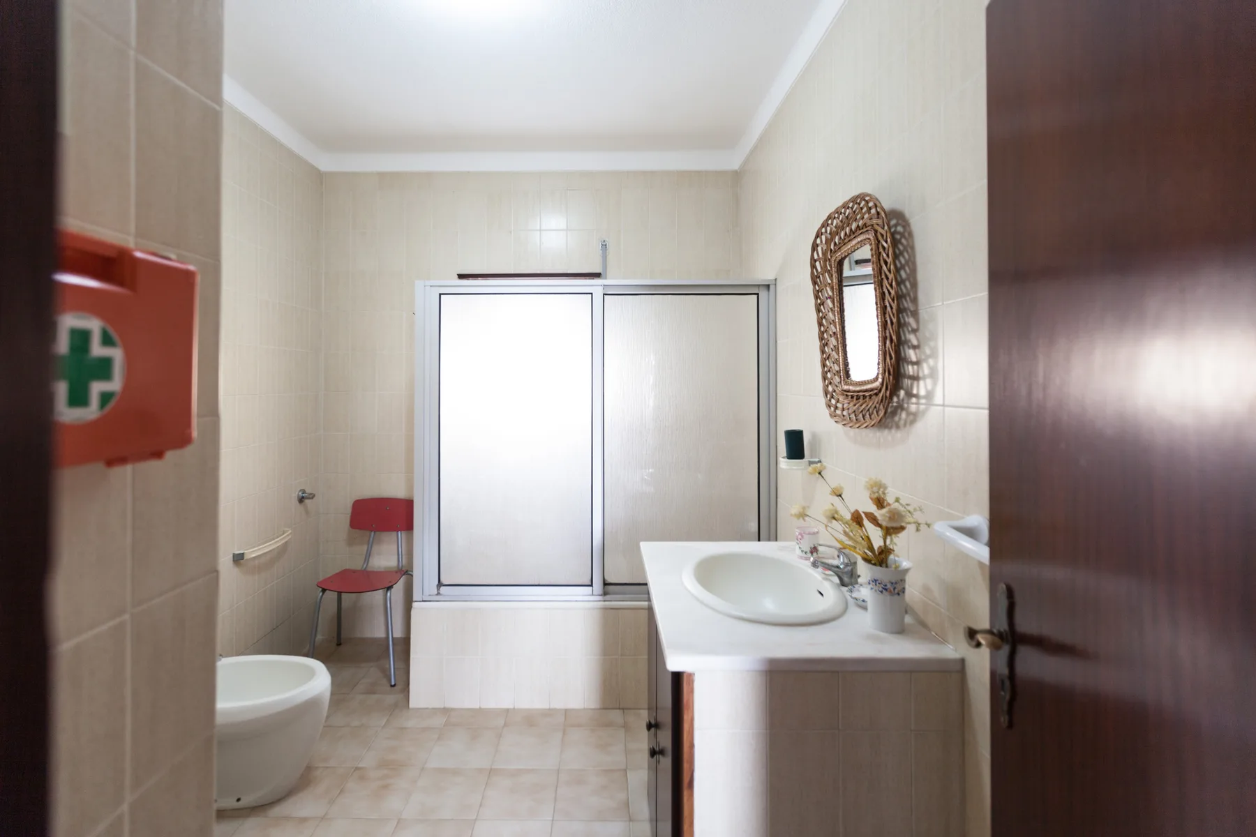 A bathroom with a sink, mirror, and frosted sliding doors.