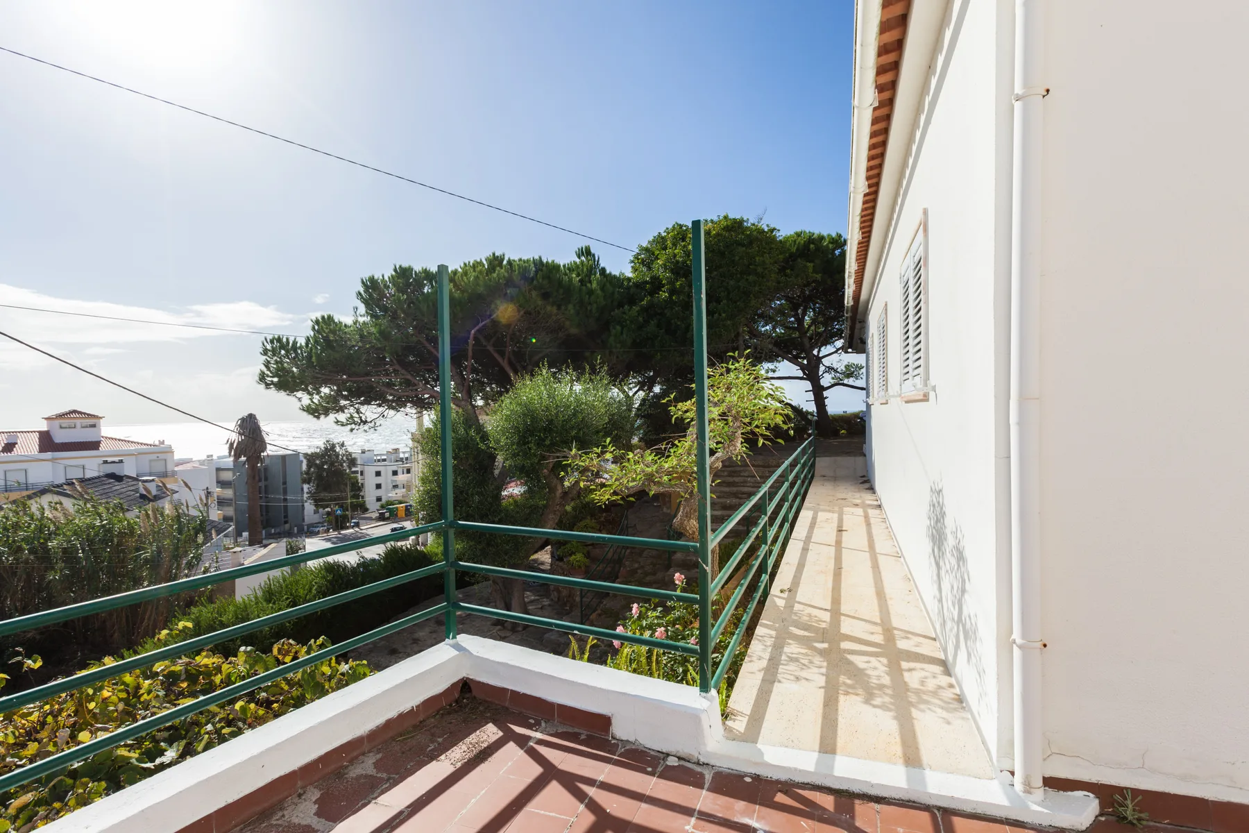 A sunny outdoor terrace overlooks trees and neighboring buildings.
