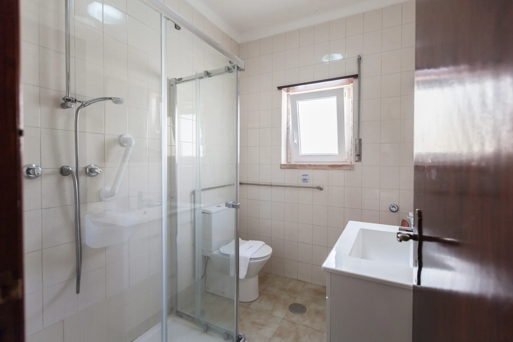 A tiled bathroom with a glass shower, toilet, and bathtub.