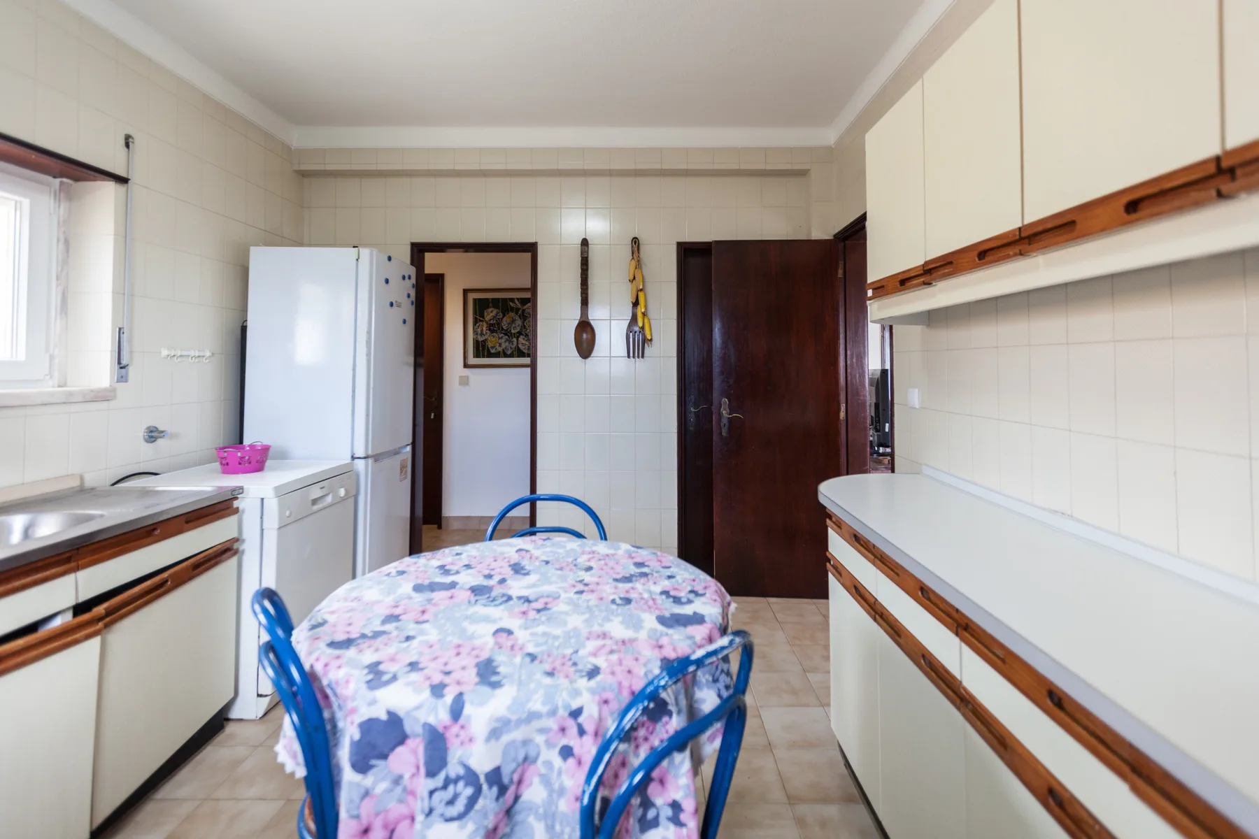 A tiled kitchen with a dining table and white cabinets.