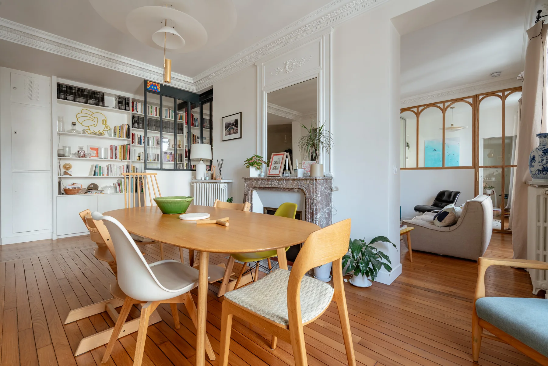 A dining area with a wooden table beside built-in shelves and an adjoining sitting area.