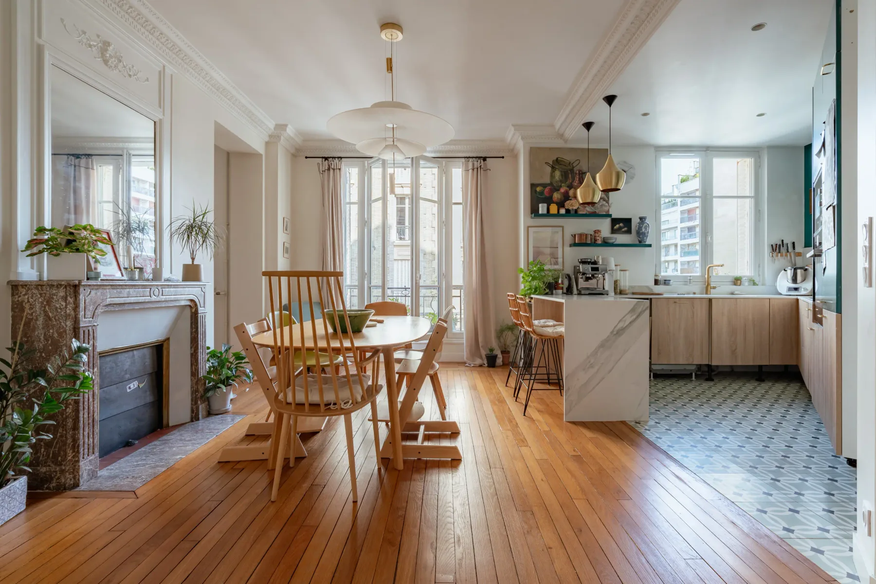 Un comedor luminoso se abre a la cocina, con una mesa junto a ventanas altas.