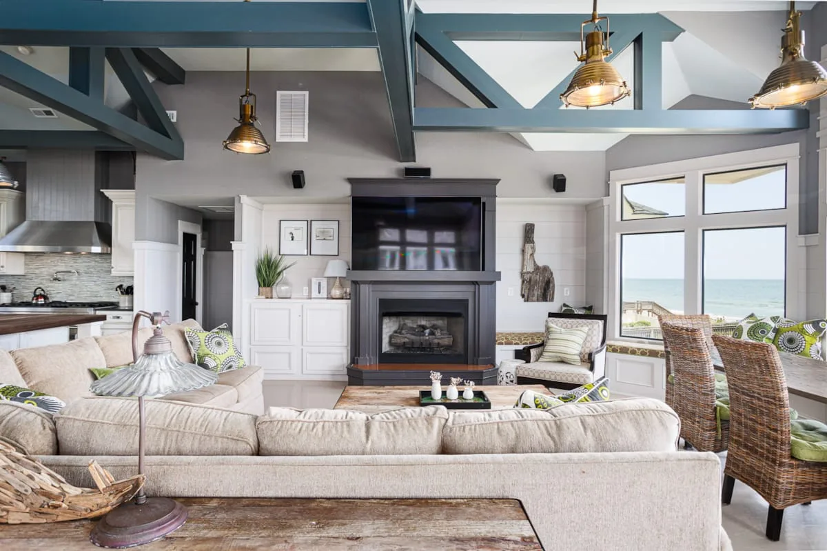 Una sala luminosa con chimenea, asientos y grandes ventanas con vistas al agua.