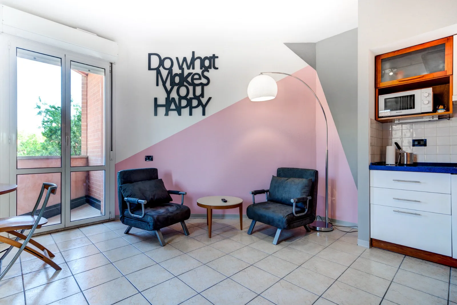 Una zona de estar con dos sillones, una mesa pequeña y una lámpara de pie.