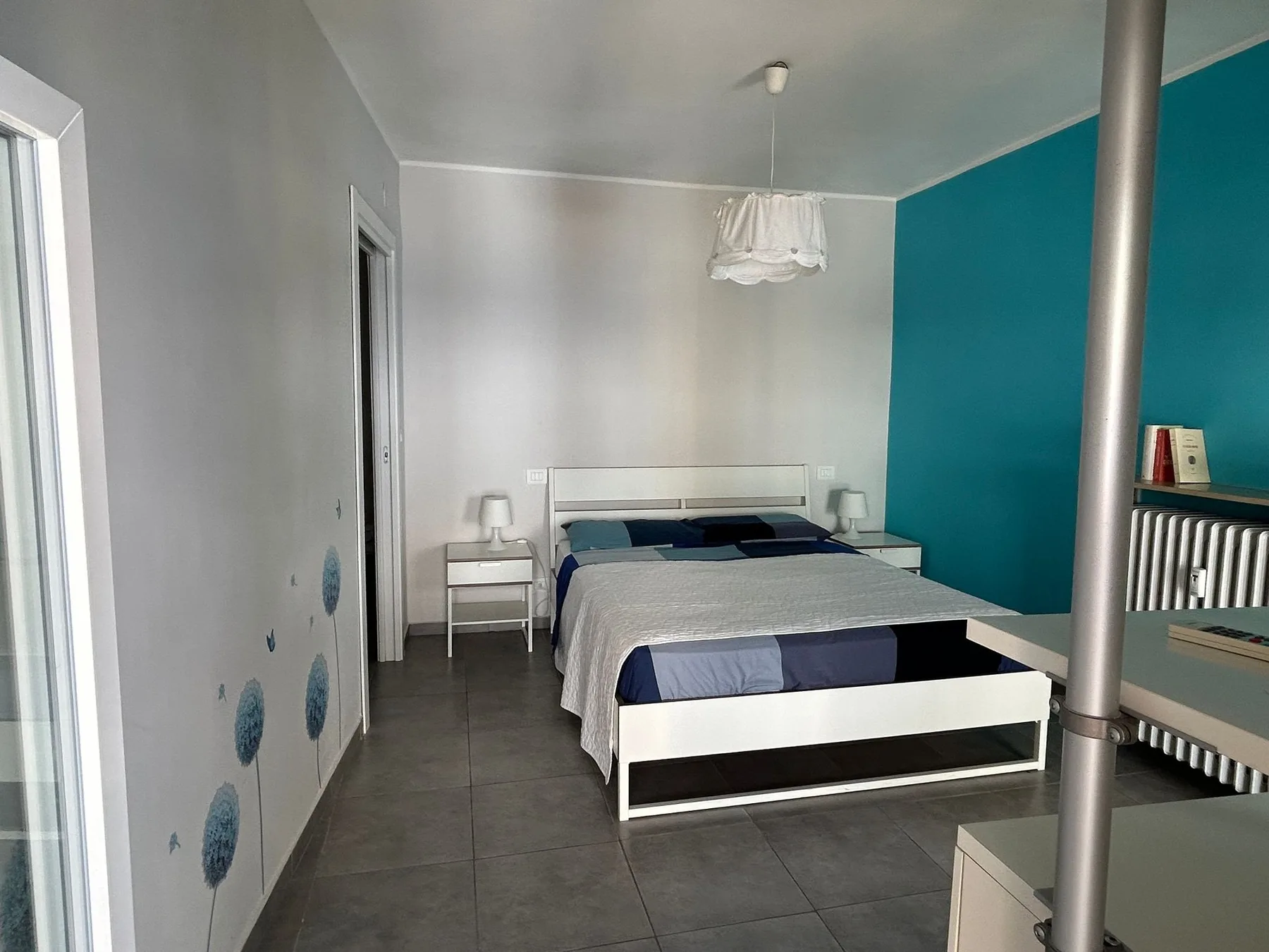 Un dormitorio con una cama doble, mesitas de noche y una pared turquesa.