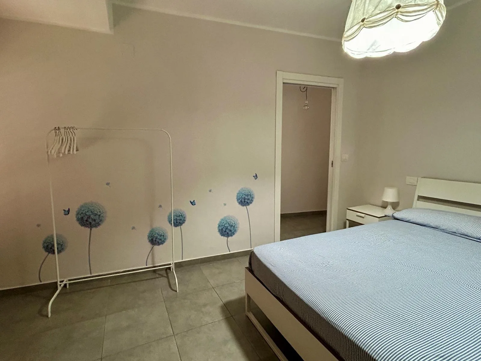 Un dormitorio con una cama y un perchero independiente junto a la pared.