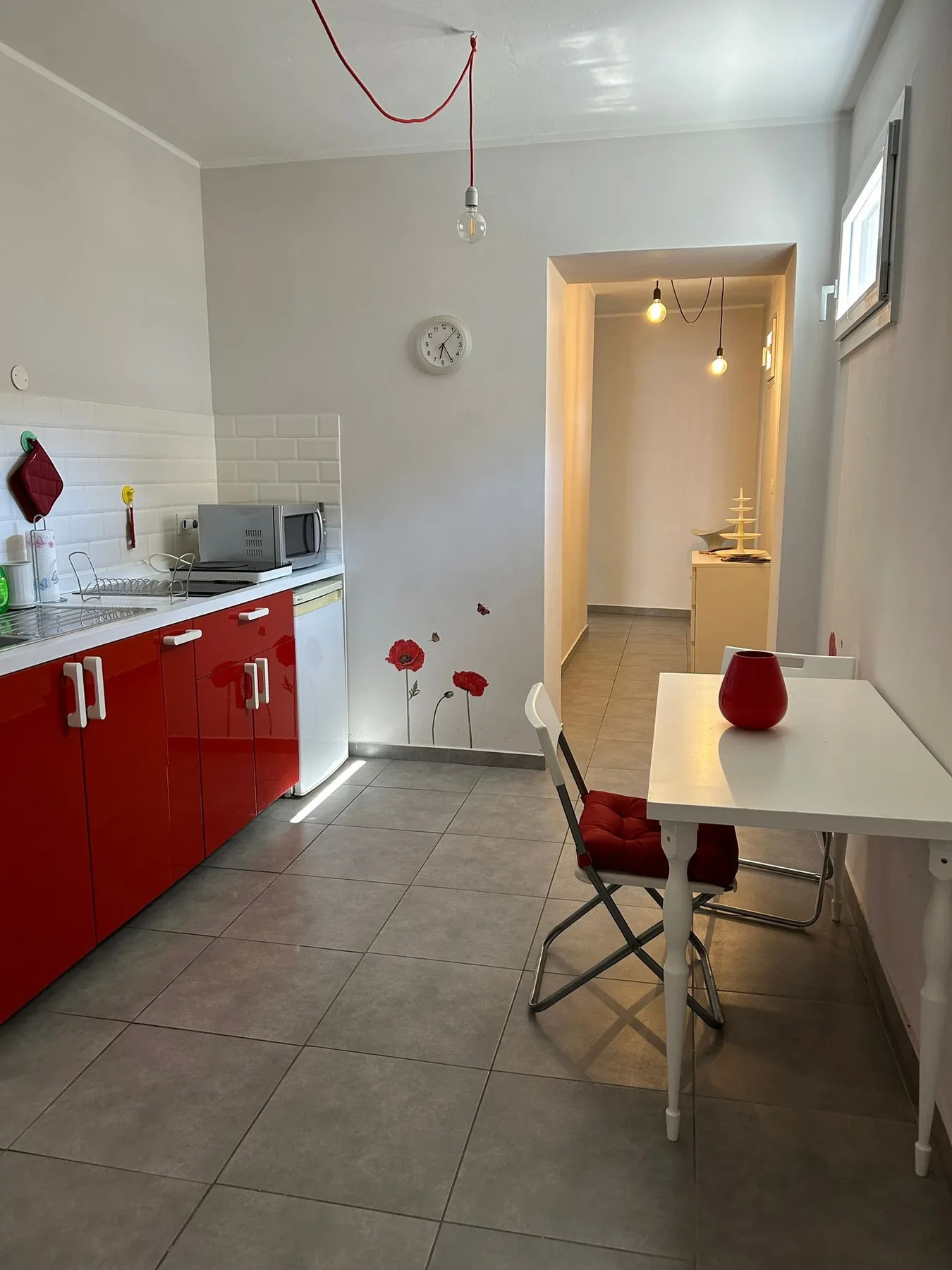 Una cocina y comedor con gabinetes rojos y una mesa.
