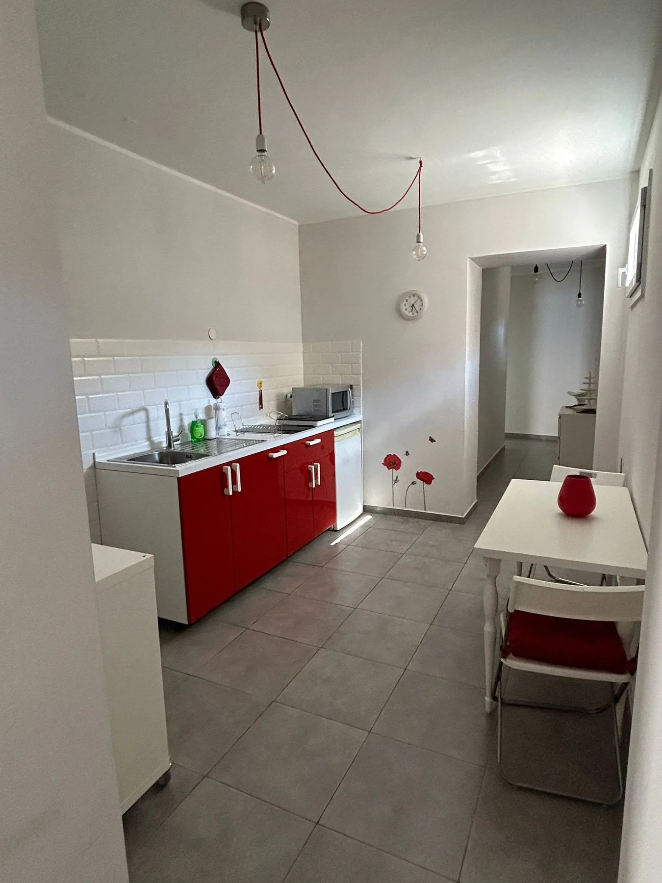 Una cocina compacta con armarios rojos y una mesa pequeña.