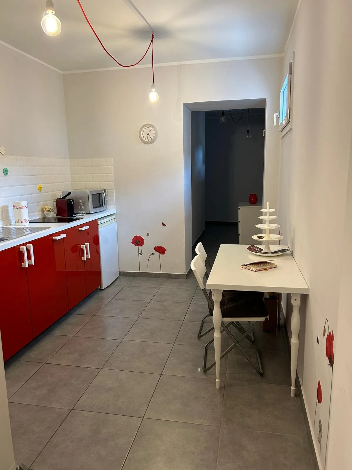 Una cocina estrecha con comedor, muebles rojos y una mesa.