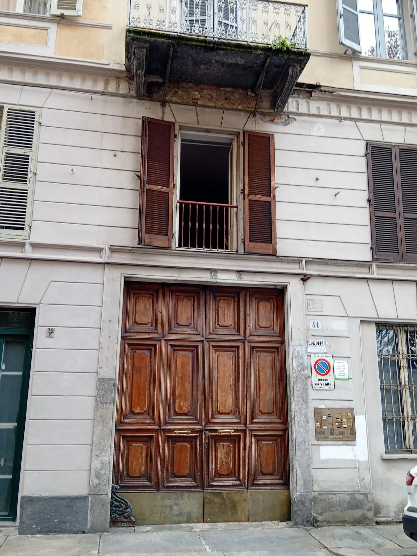 Fachada de un edificio con una gran entrada de madera y una ventana superior abierta.