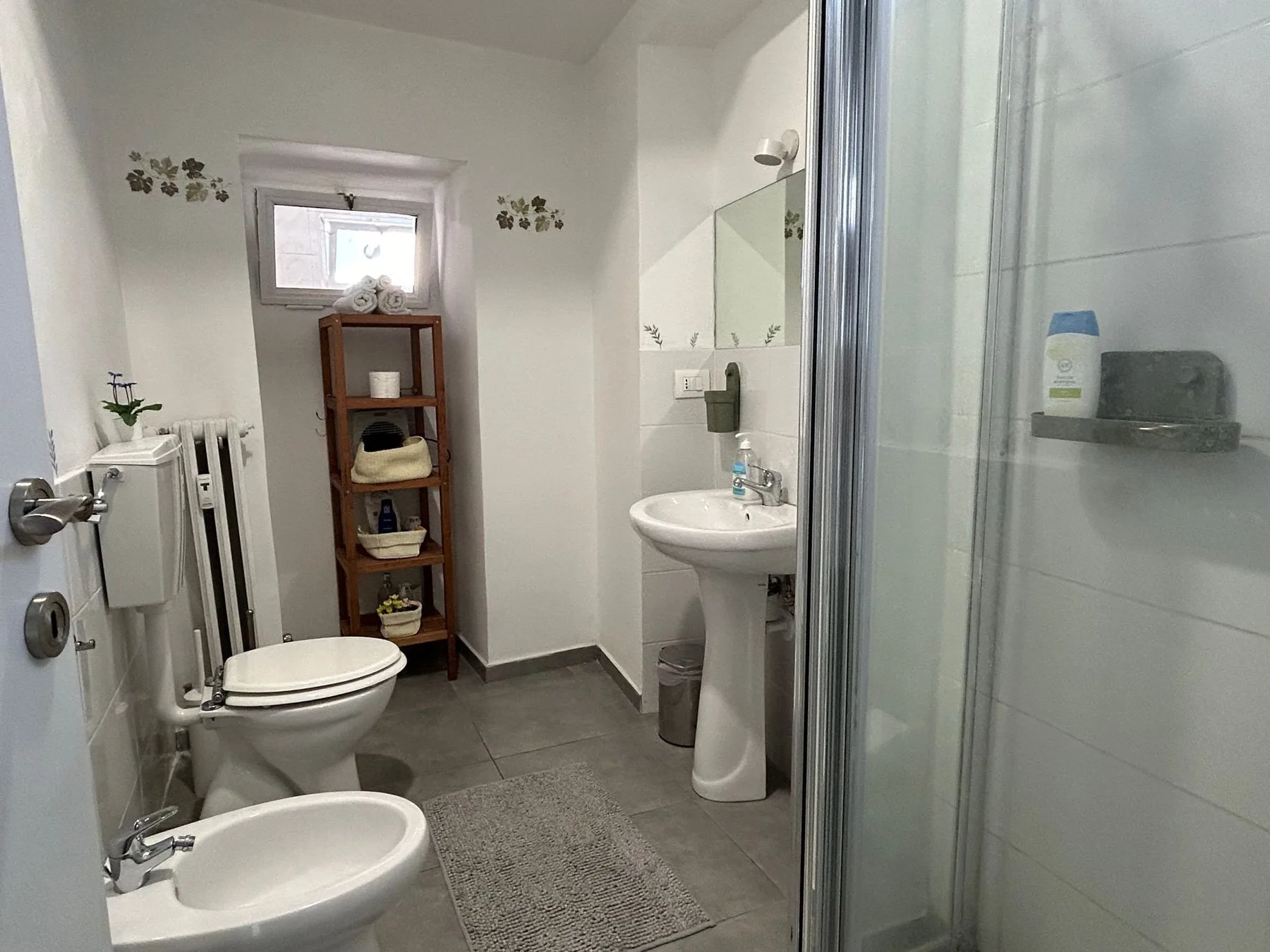 Un baño compacto con inodoro, lavabo y ducha de vidrio.