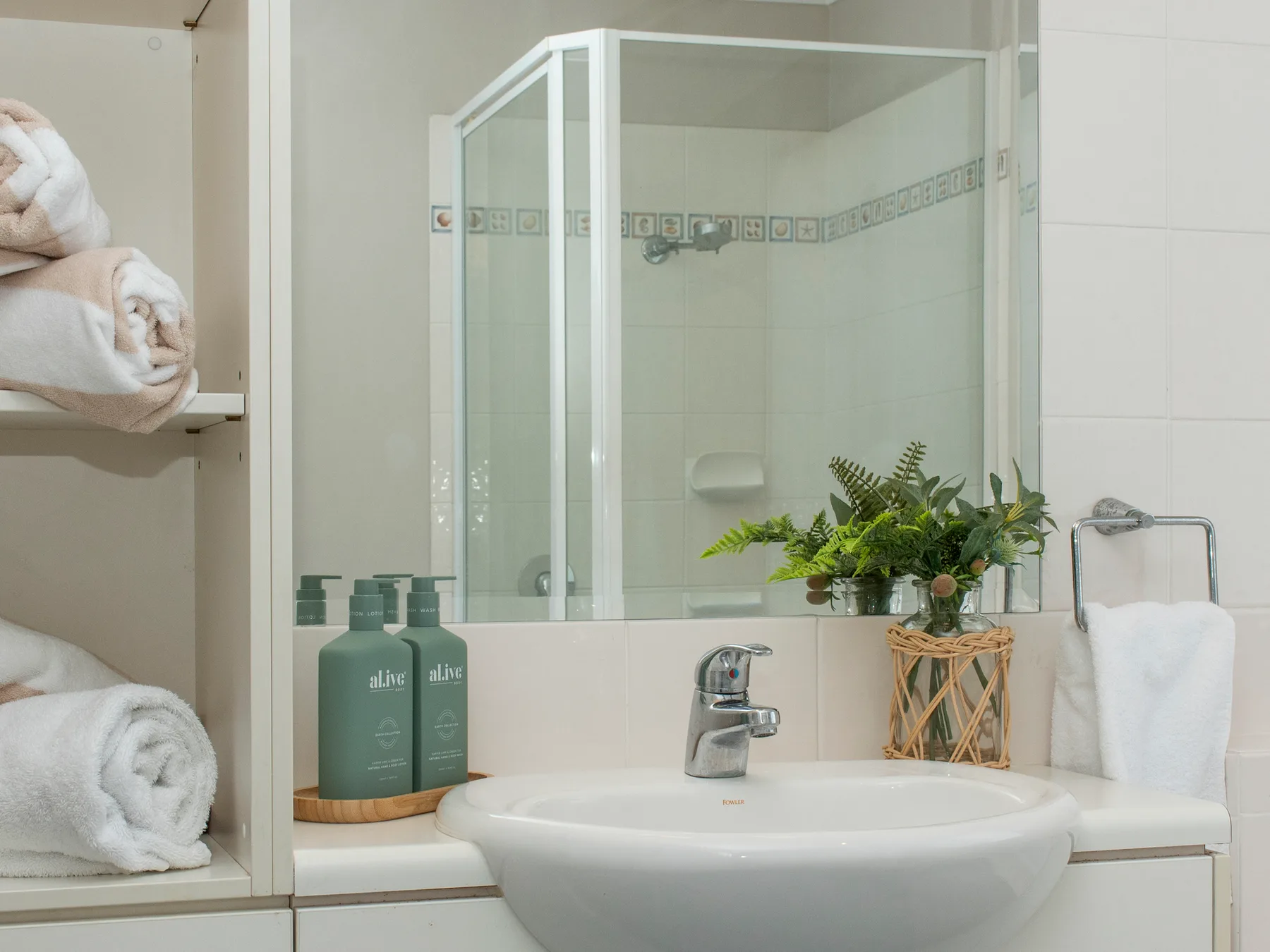 A bathroom sink sits beneath a mirrored cabinet beside a glass shower.