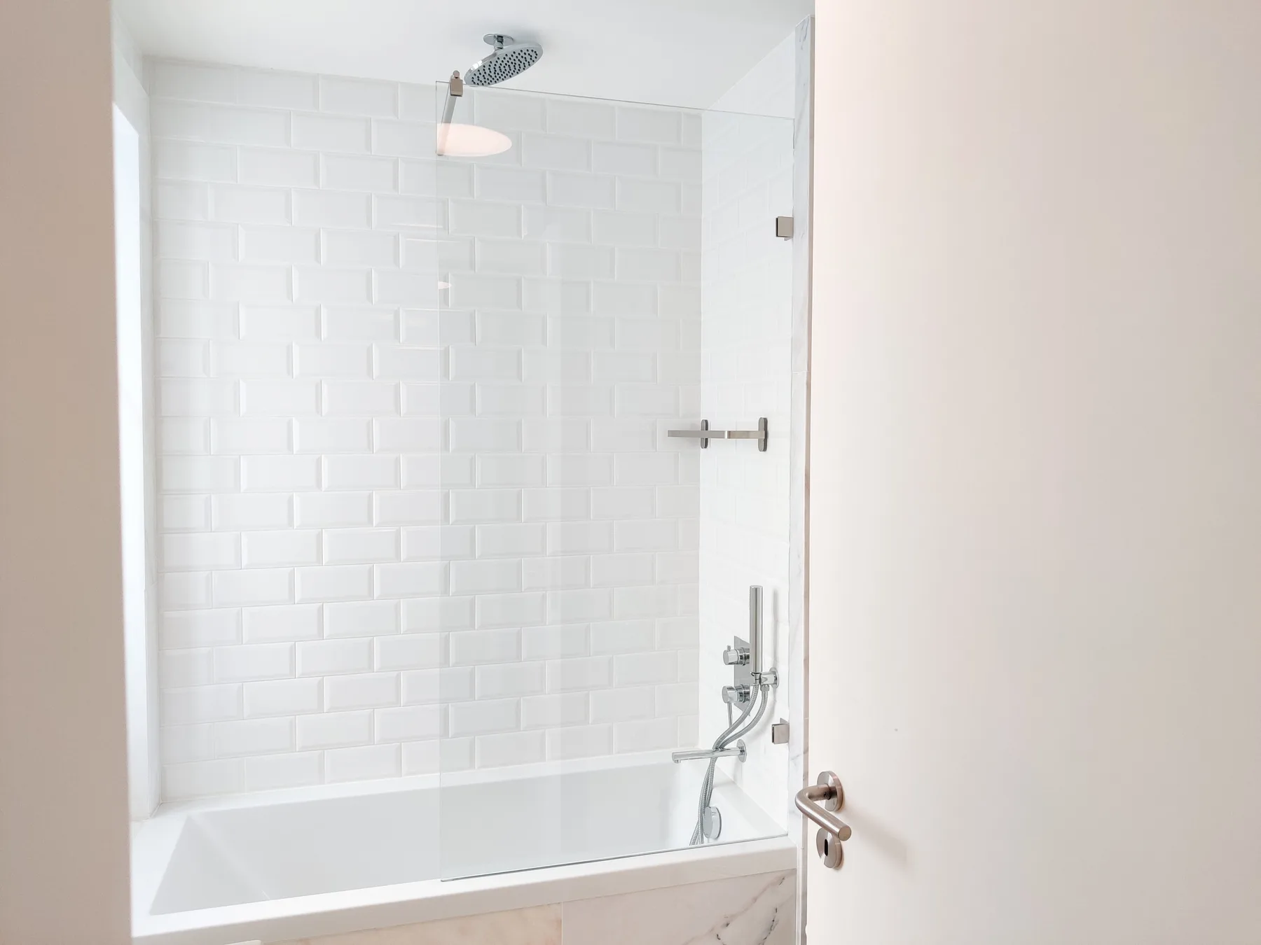 A bright bathroom features a bathtub and a wall-mounted shower.