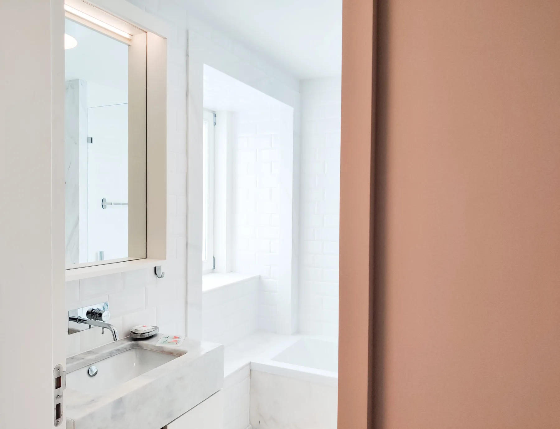 A bright bathroom with a sink, mirror, and shower.
