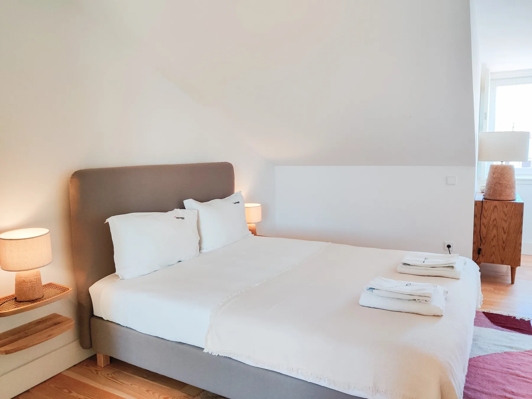 A bedroom with a neatly made bed and folded towels.
