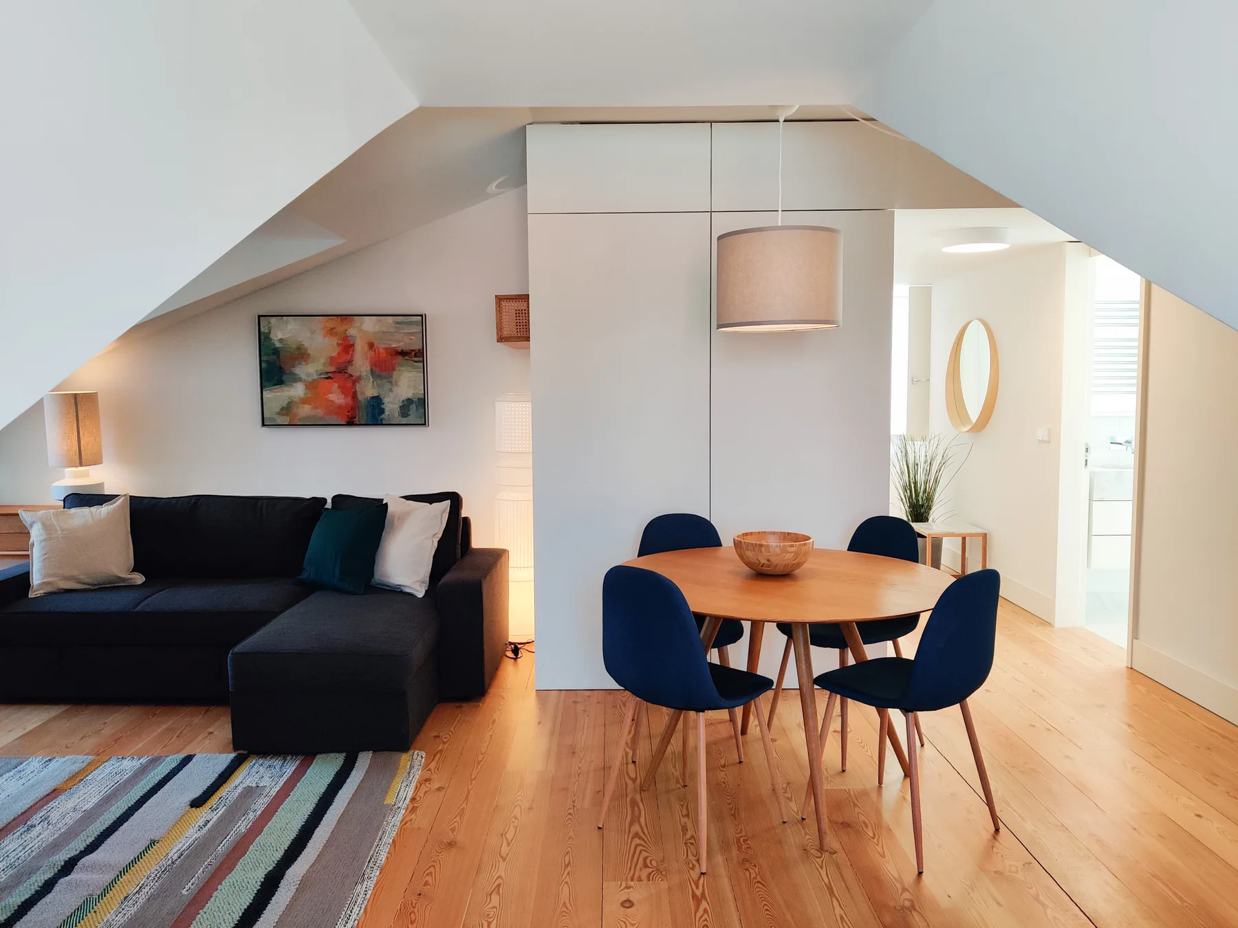A living and dining area with a dark sofa and a round wooden table.