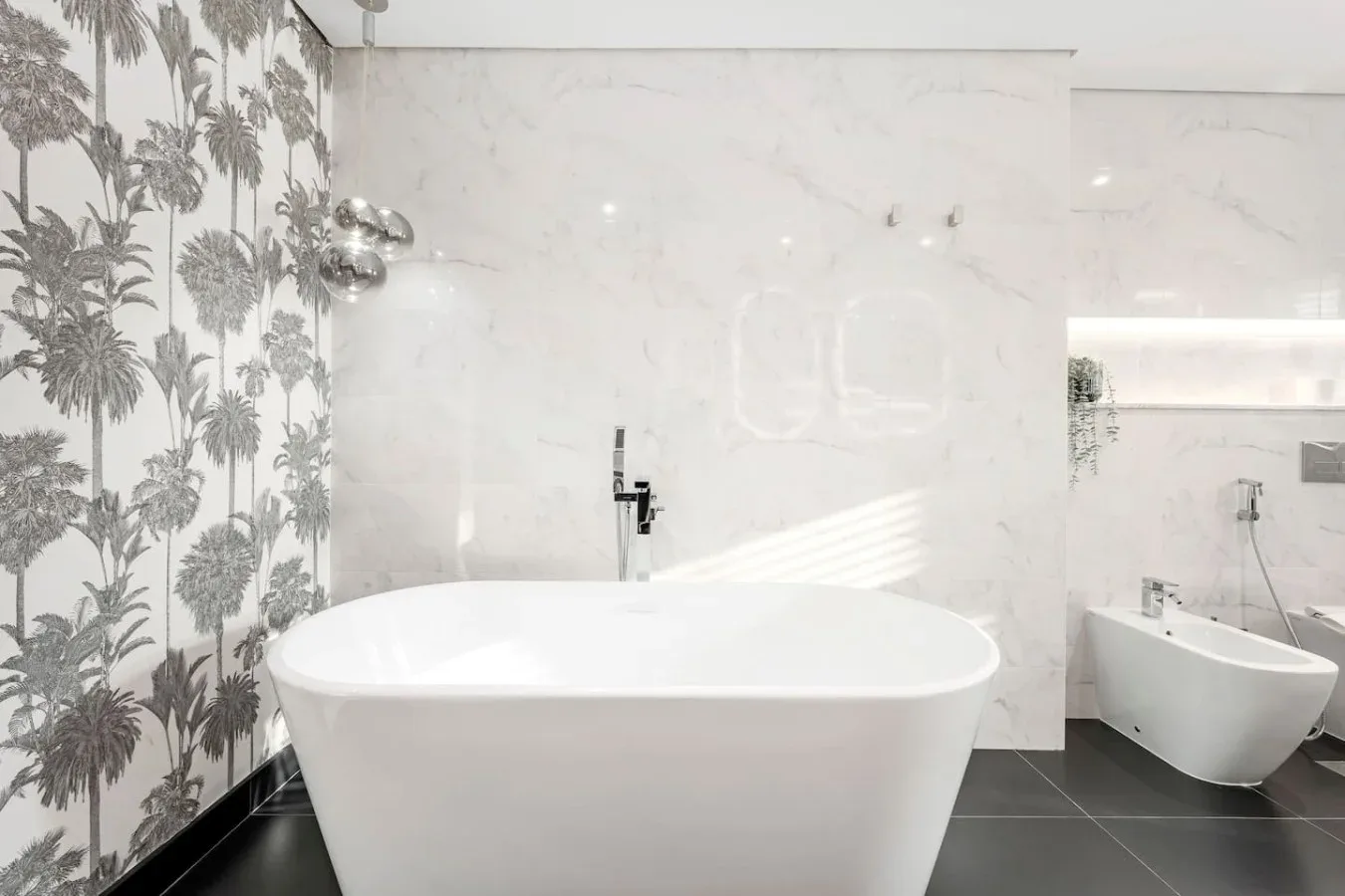 A bright bathroom with a freestanding bathtub and patterned wall covering.