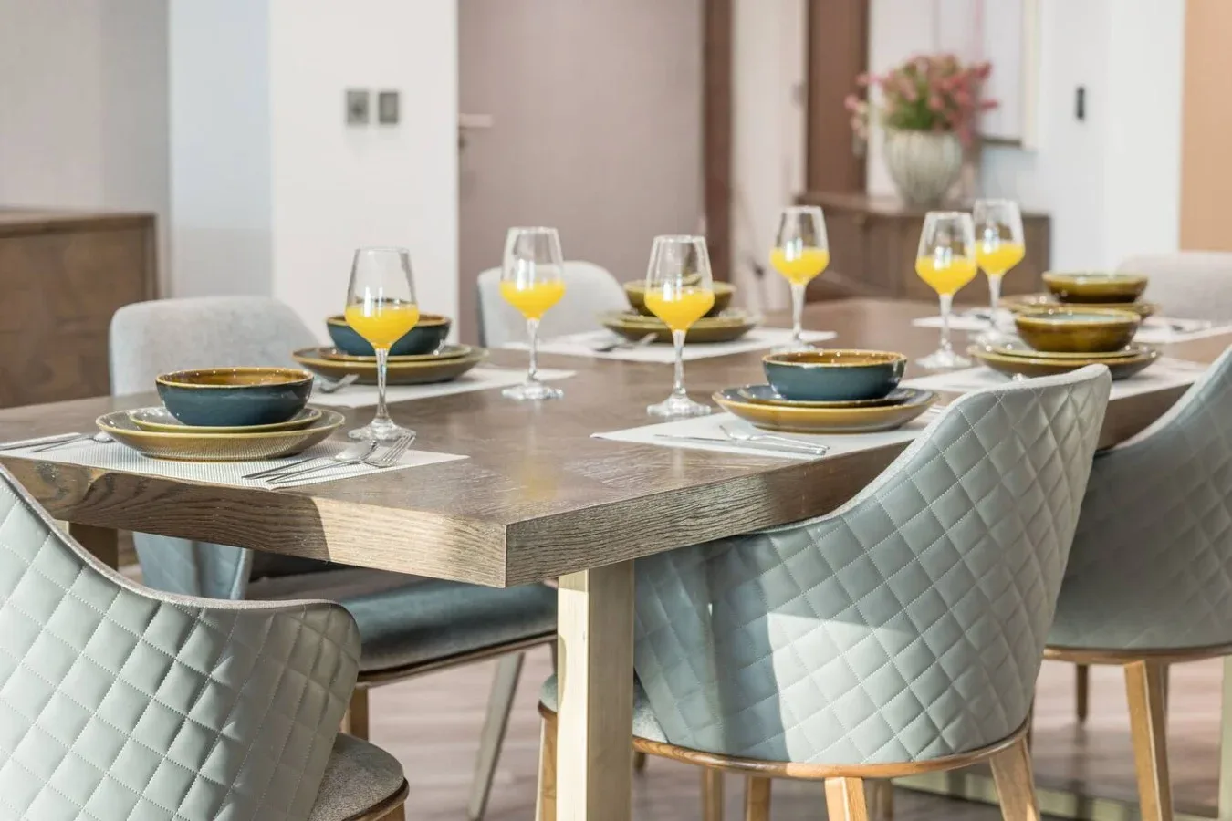 A dining area with a set table and upholstered chairs.