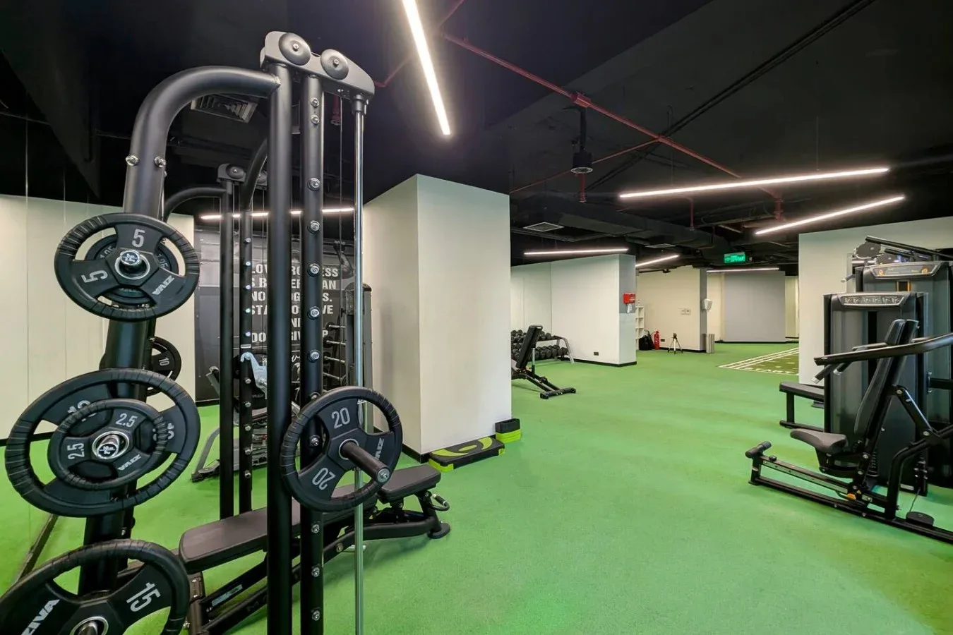 A gym with weight-training equipment on a green floor.