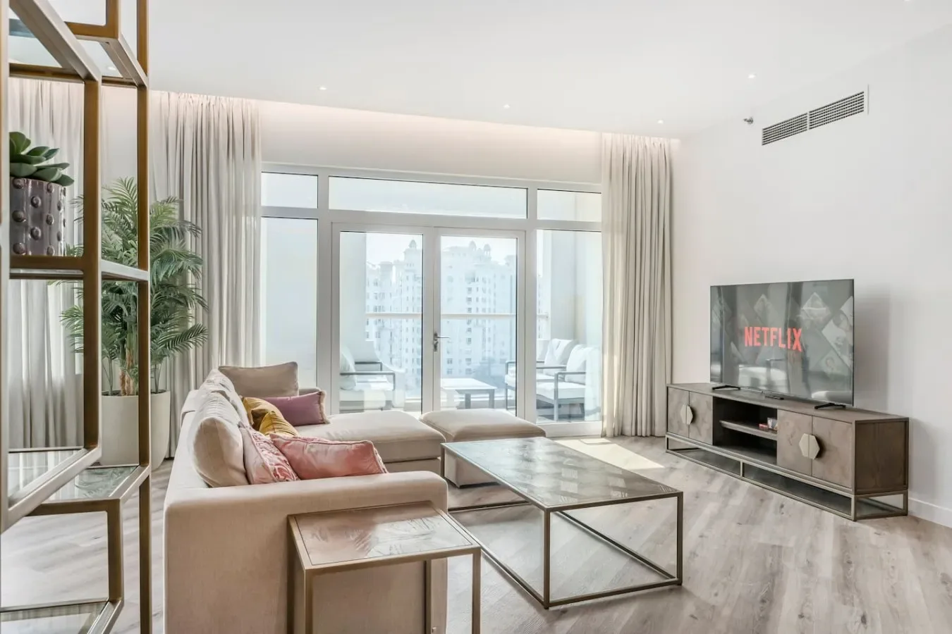 Una sala luminosa con asientos, una mesa de centro de vidrio y un televisor.