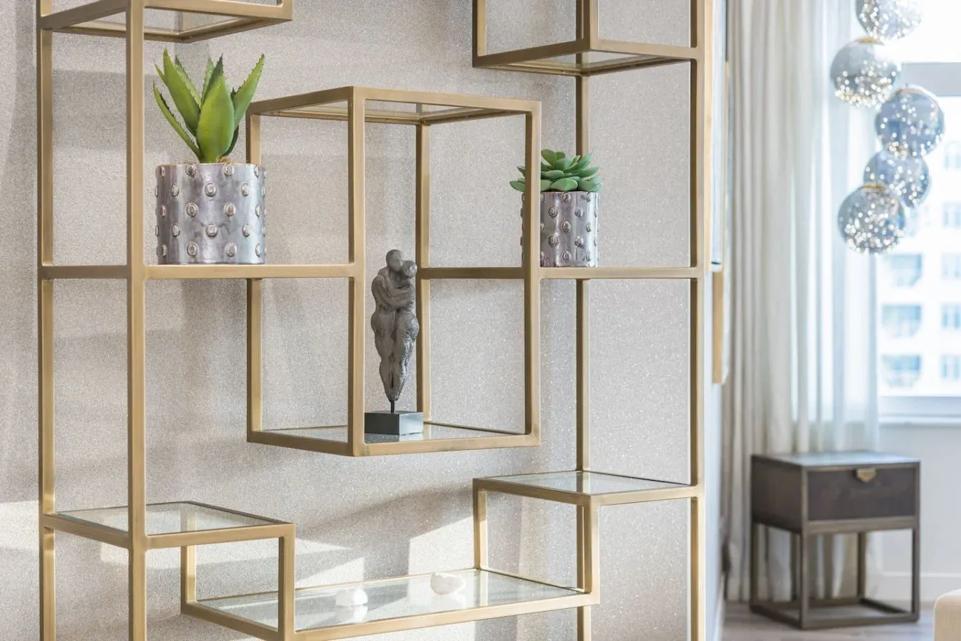 A bright interior features open geometric shelving with plants and a small sculpture.