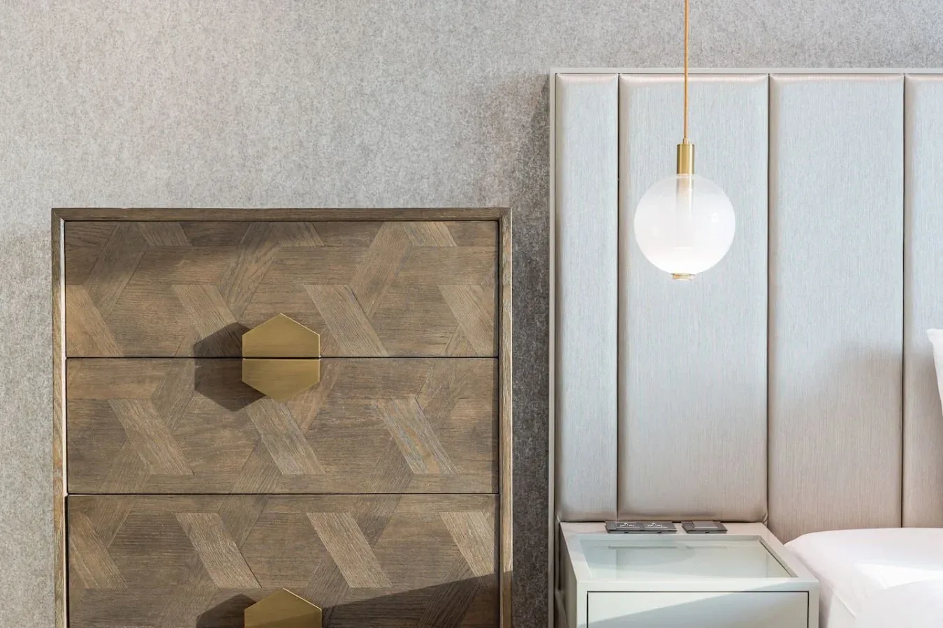 A bedroom corner with a patterned dresser and a hanging globe light.