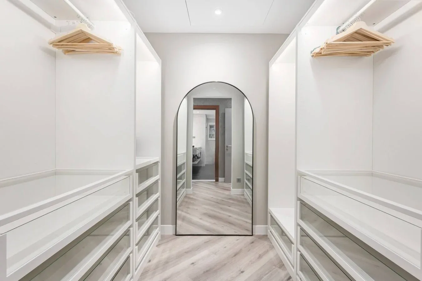 A bright walk-in closet with built-in shelving and hanging rails.