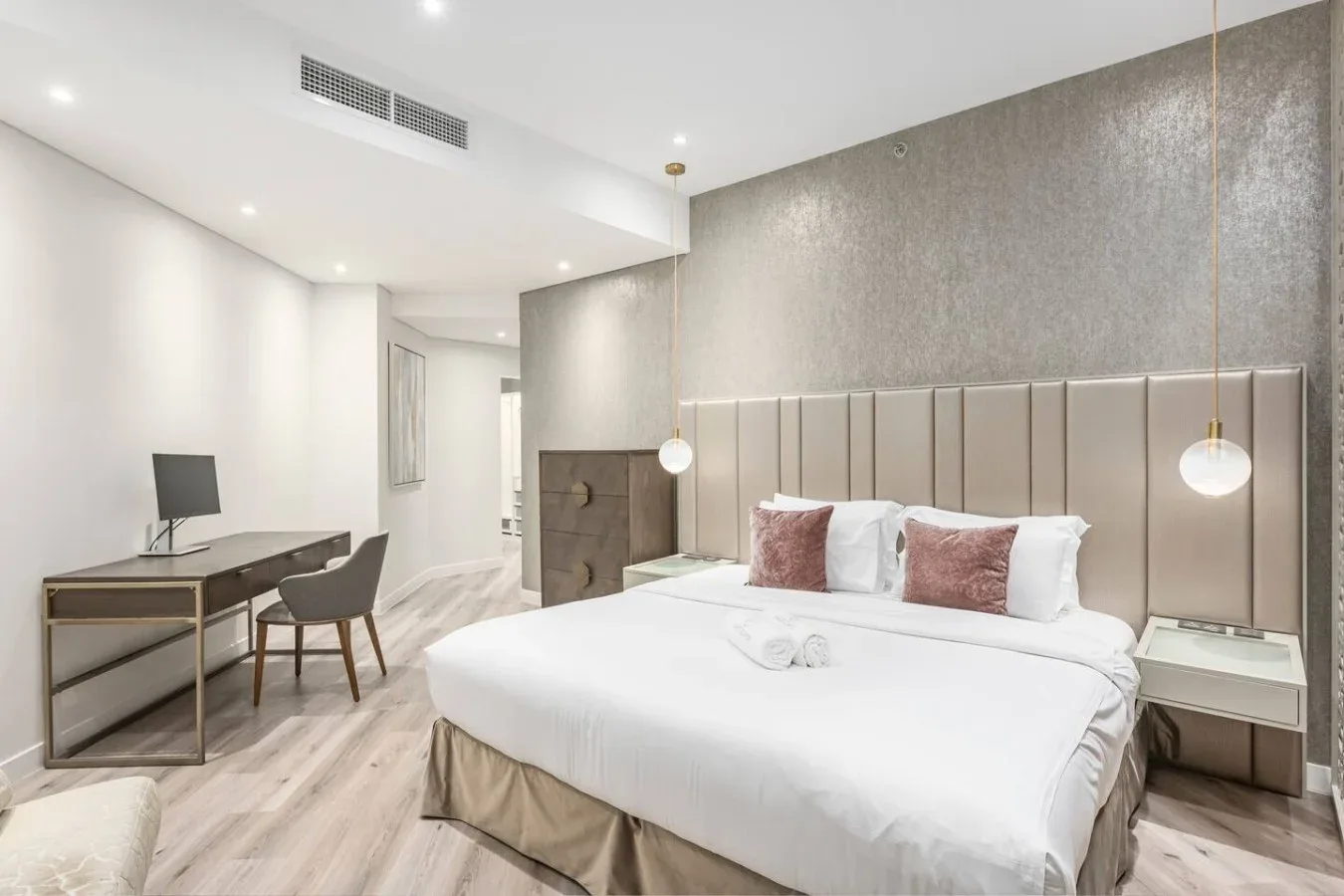A bright bedroom with a large bed, bedside tables, and a desk.
