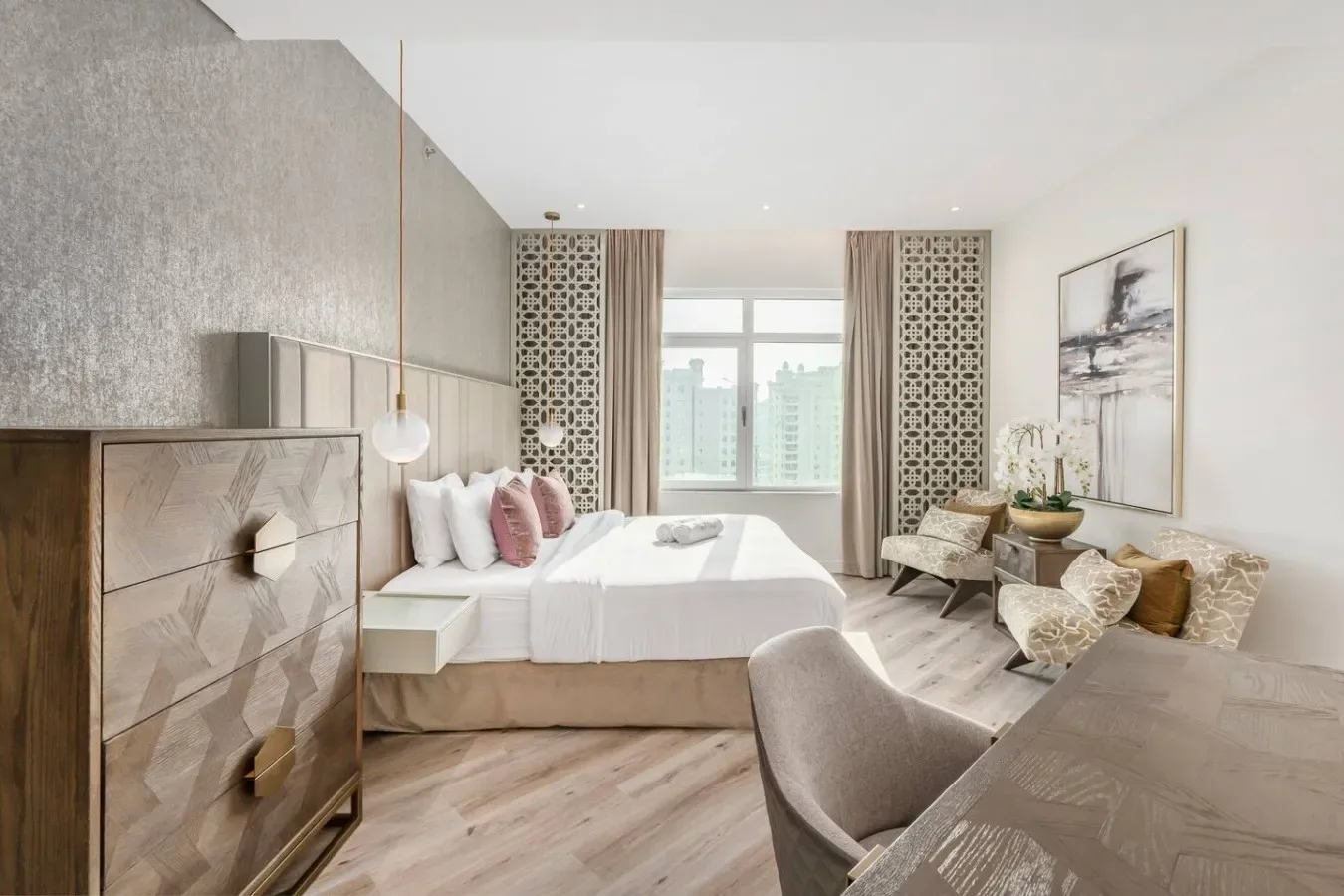 A bright bedroom with a large bed, window, and seating area.