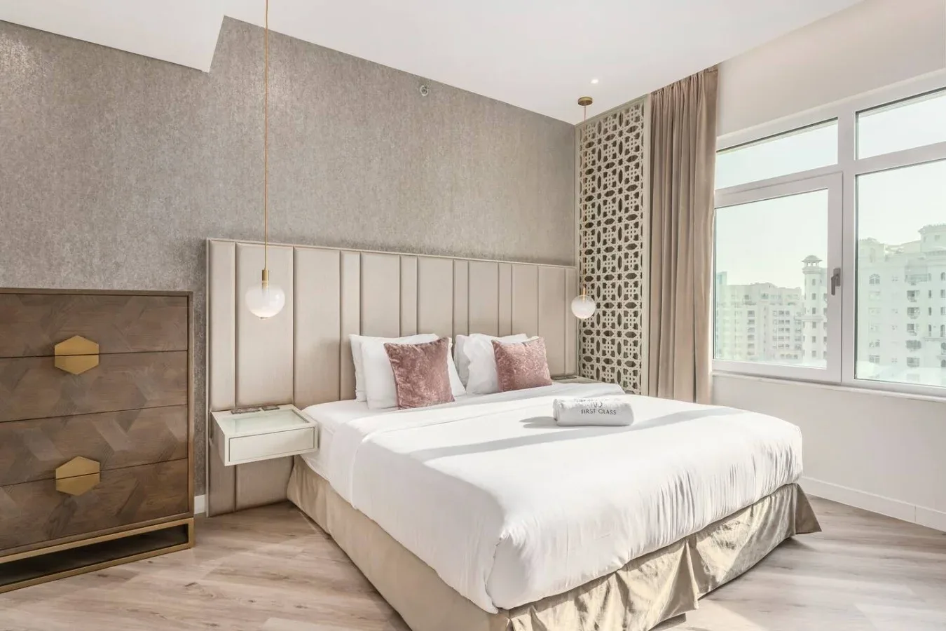 A bright bedroom with a large bed beside broad windows.