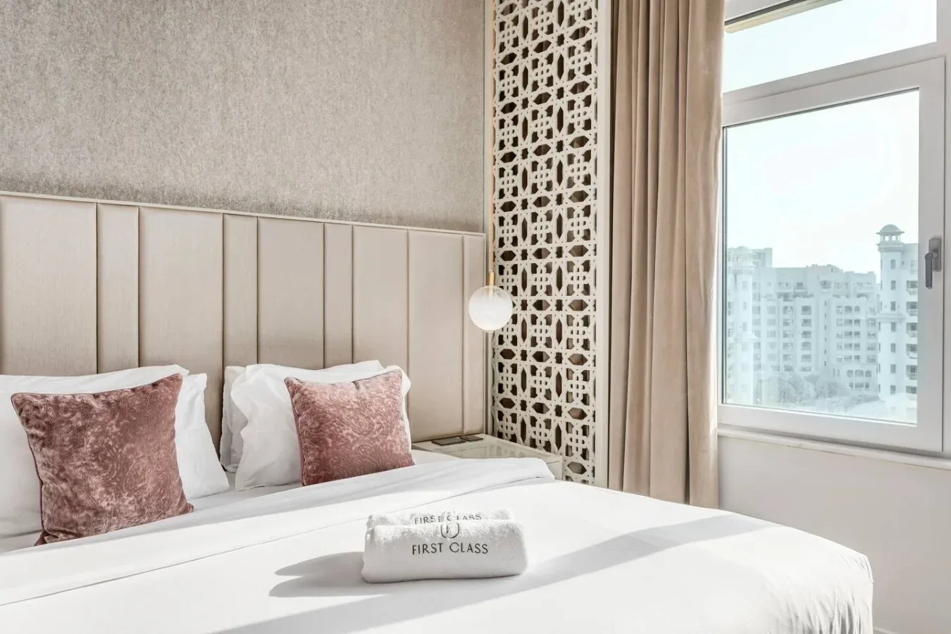 A bedroom with a neatly made bed beside a large window.