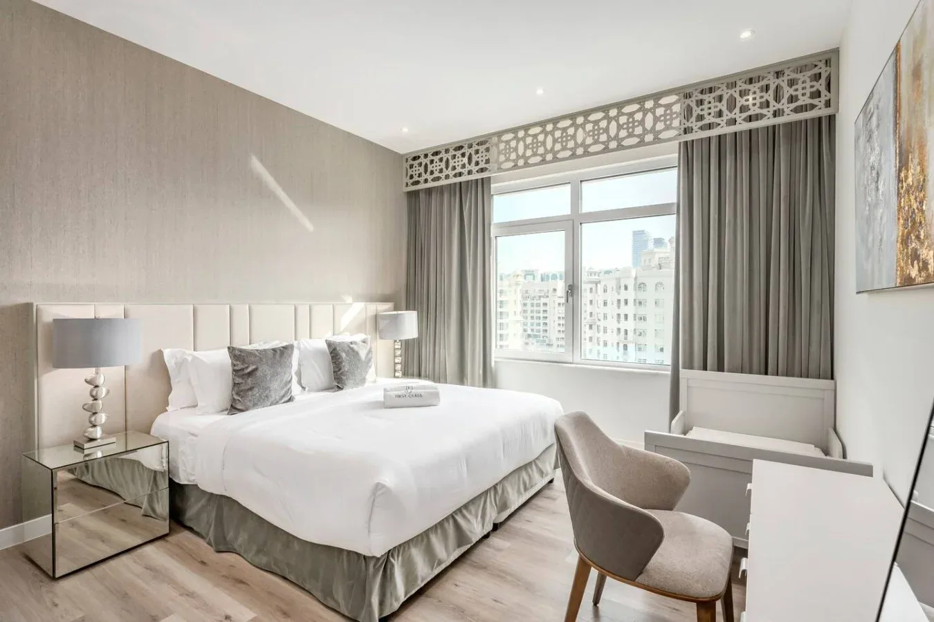 A bright bedroom with a neatly made bed beside a large window.