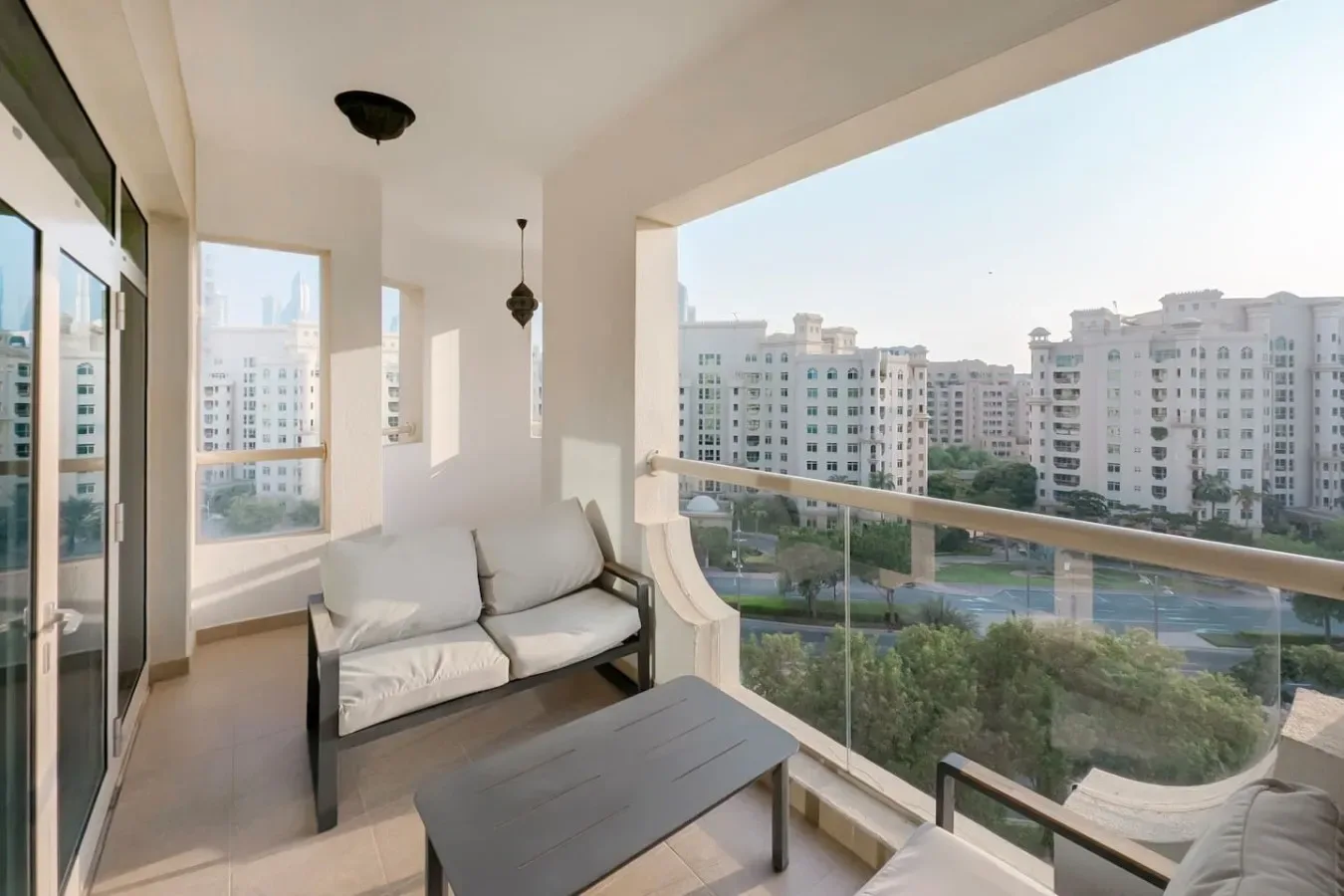 Una zona de estar en el balcón da a edificios de apartamentos y áreas ajardinadas.