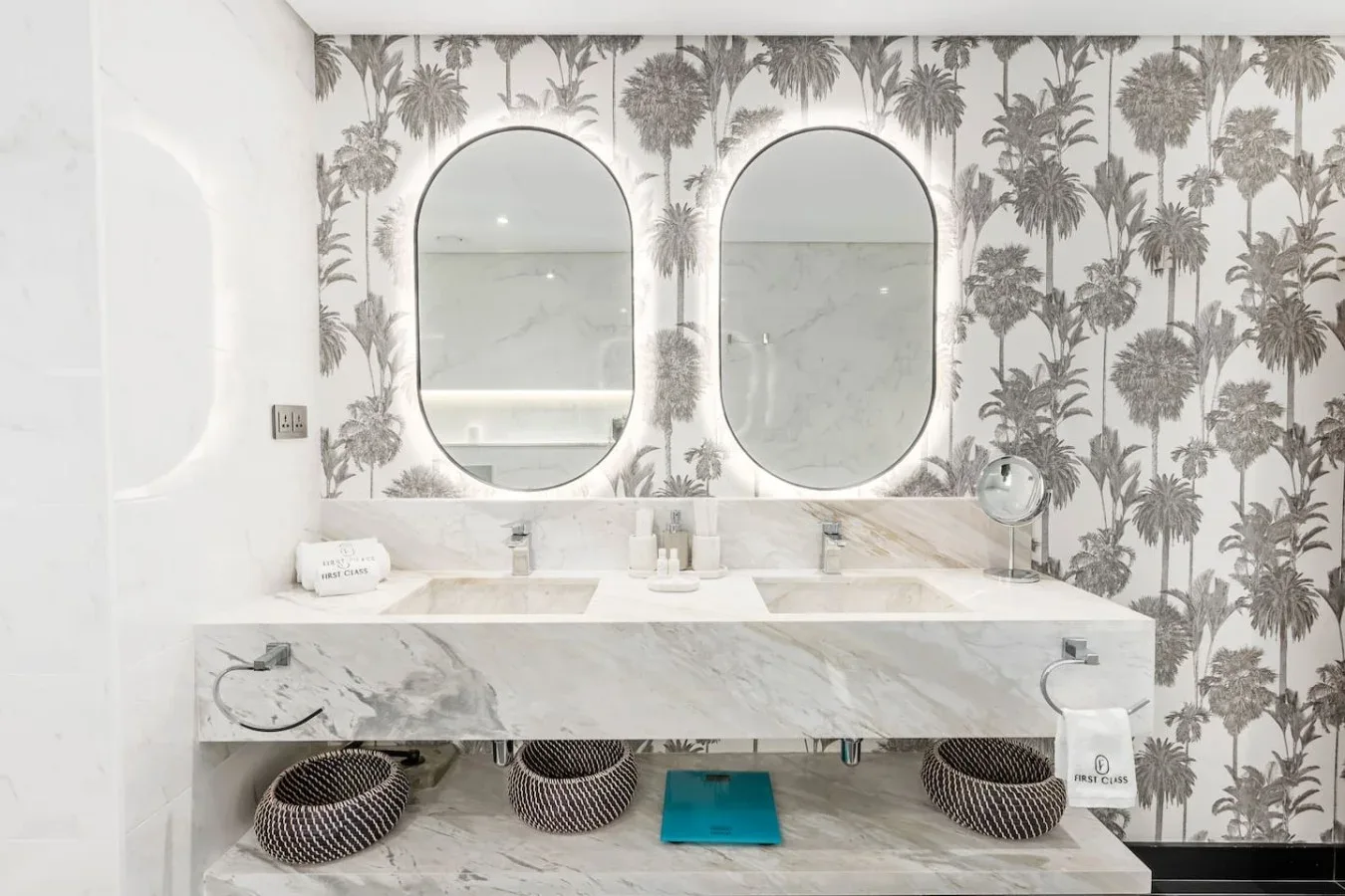 A bright bathroom with twin mirrors above a long marble vanity.