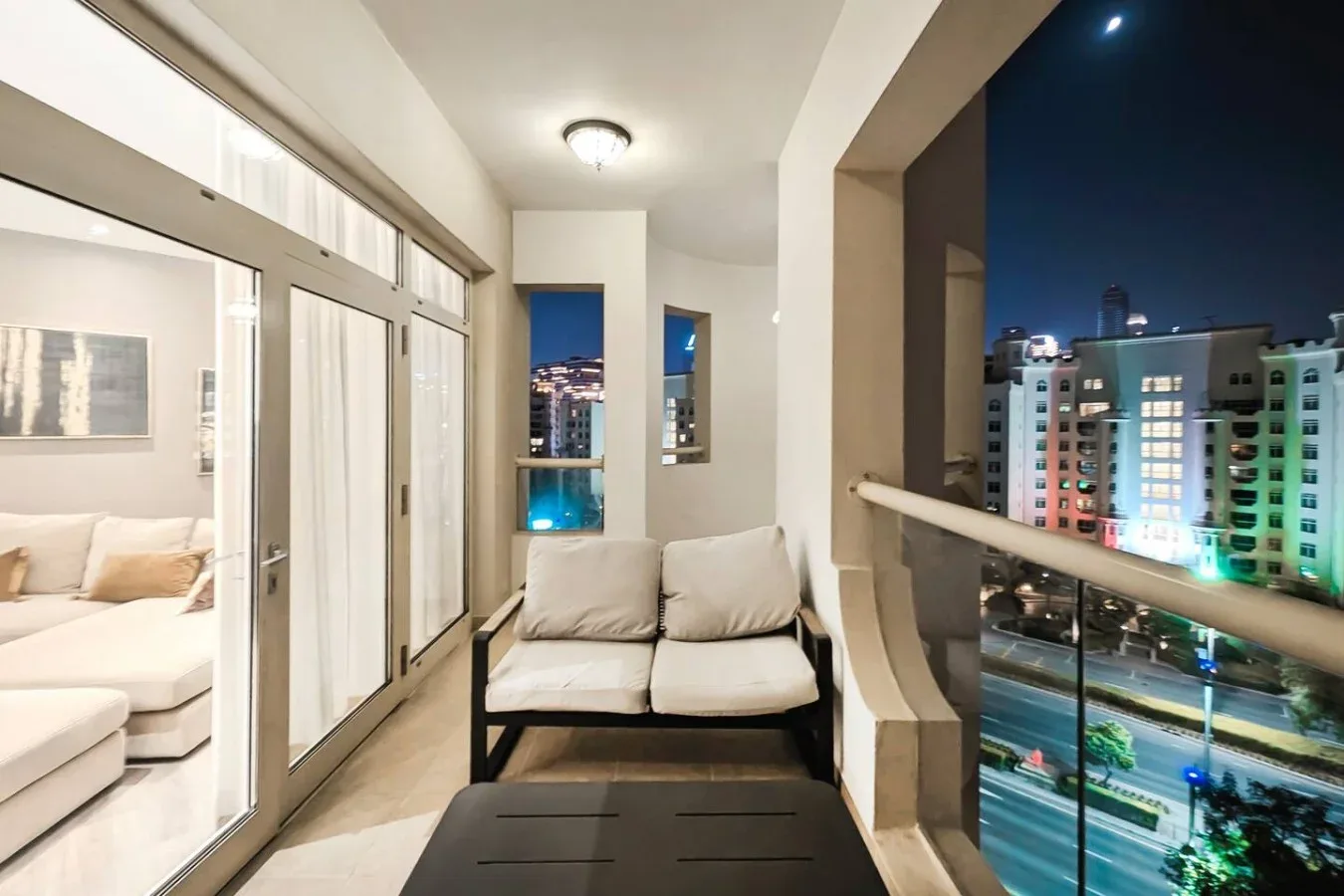 A balcony seating area overlooks illuminated buildings at night.