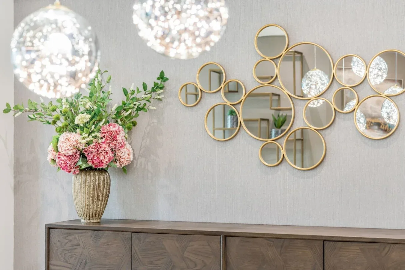 A decorative console stands beneath a wall arrangement of round mirrors.
