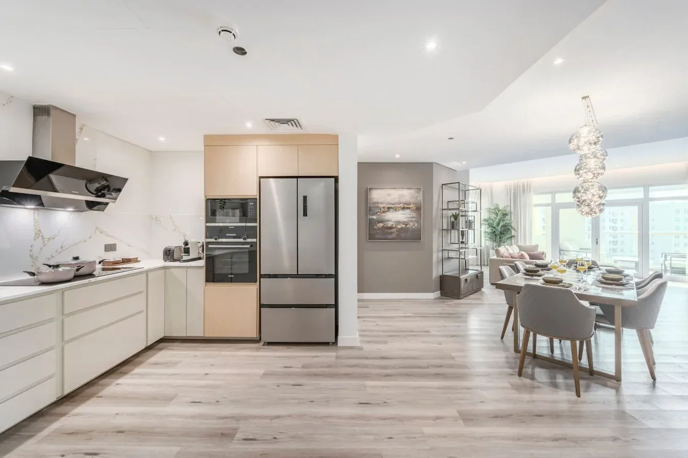 An open-plan kitchen and dining area with large windows and light wood flooring.