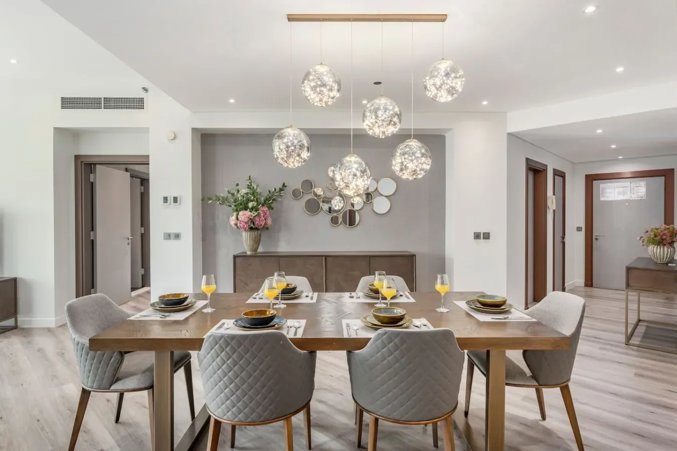 Un comedor luminoso con una mesa larga y lámparas colgantes decorativas.