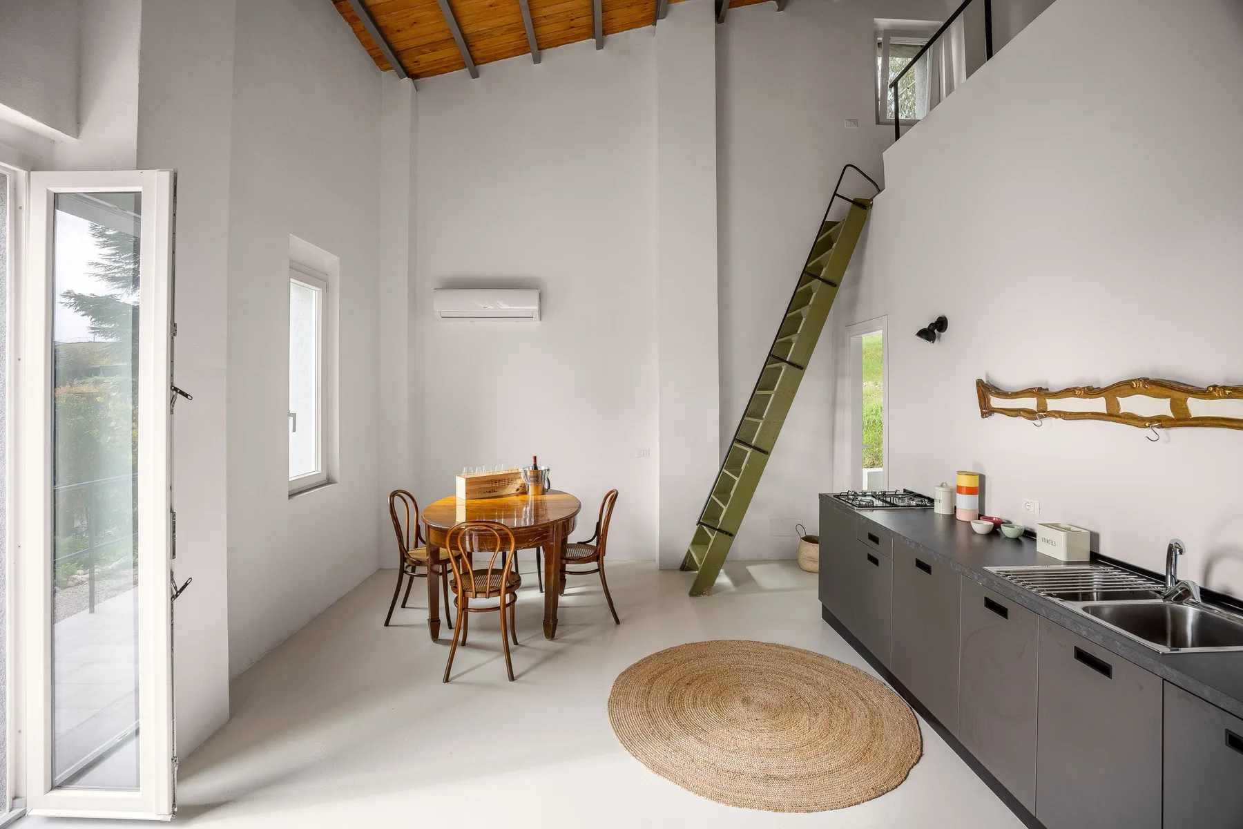 Una cocina y comedor diáfanos y luminosos, con una mesa de madera y una alfombra redonda tejida.
