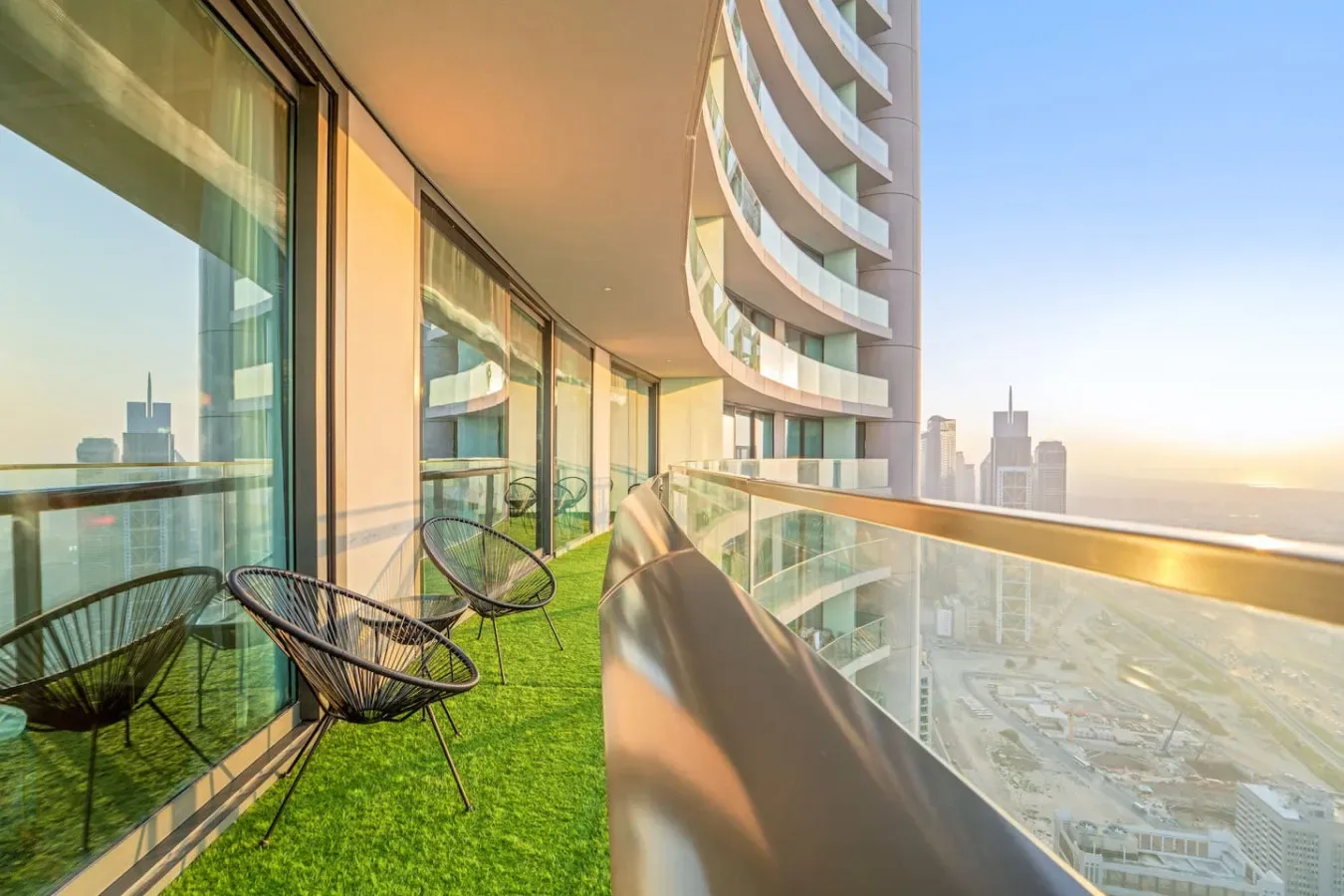 A curved balcony with glass railings overlooks a city skyline.